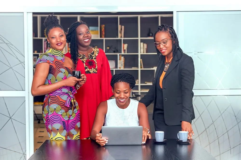 A group of women professionals collaborating around a laptop